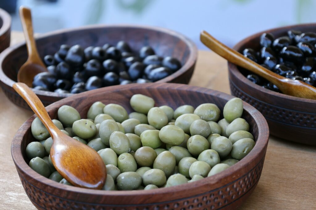 Close-up of green and black olives in wooden bowls, perfect for culinary themes.